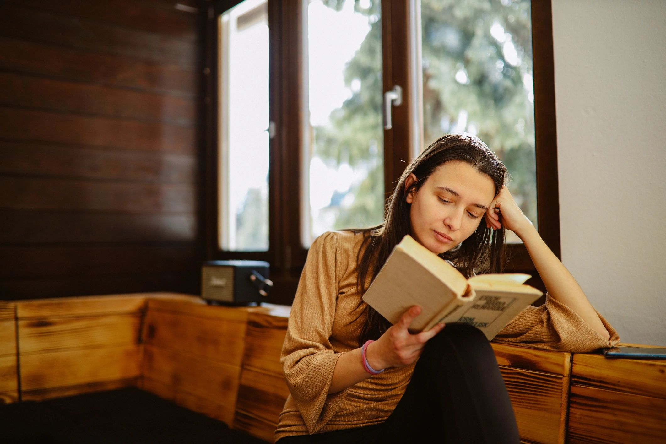 Woman reading a book in a mountain cabin