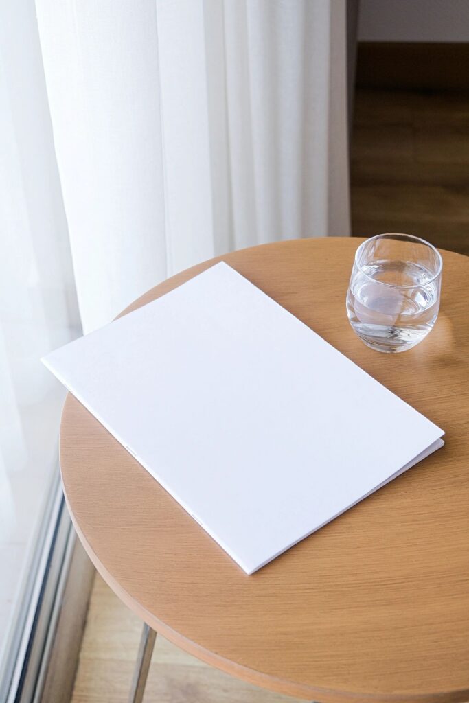 magazine mockup design. blank book mockup on wooden coffee table with glass of water