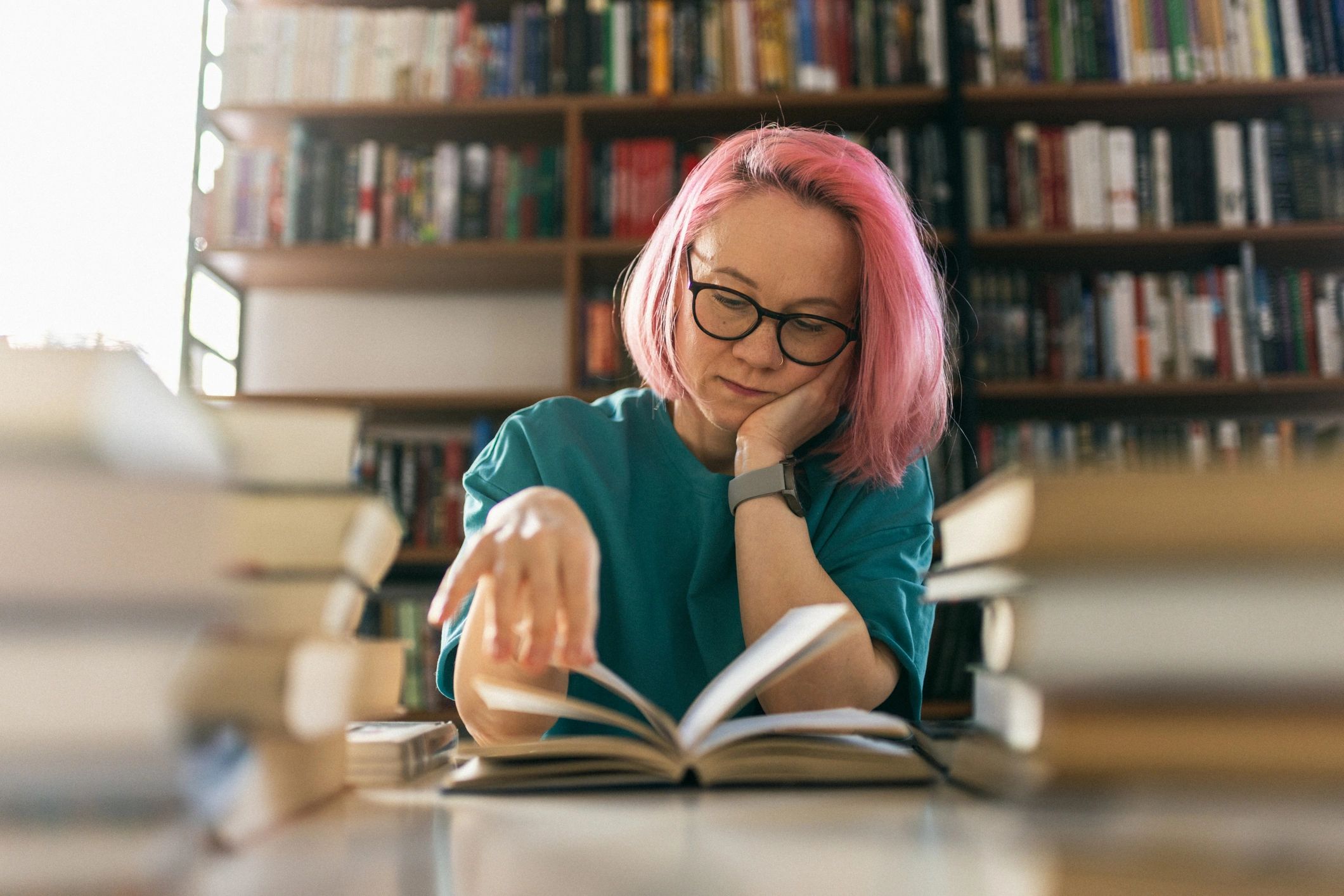 Reader at a table surrounded by books