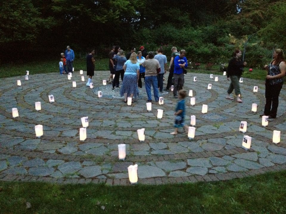 Guests walking a candlelit labyrinth during an outdoor evening gathering